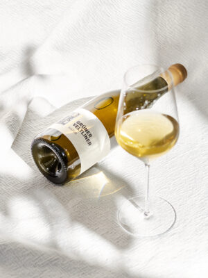 Grüner Veltliner Natur vom Weingut Faber-Köchl: Flasche liegt neben einem Bordeaux-Glas mit goldgelbem Wein