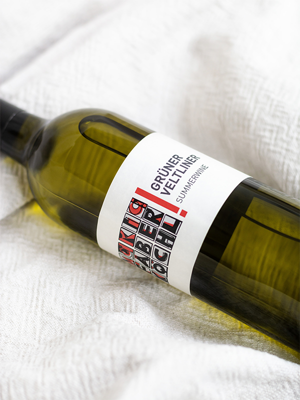 Eine Flasche Grüner Veltliner Summerwine vom Weingut Faber-Köchl liegend auf einer weißen Decke
