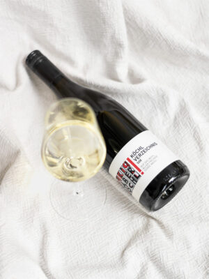 Eine Flasche der Weißwein-Cuvée Köchl Verzeichnis 508 Auf das Wohl aller Freunde vom Weingut Faber-Köchl liegend auf einer weißen Decke