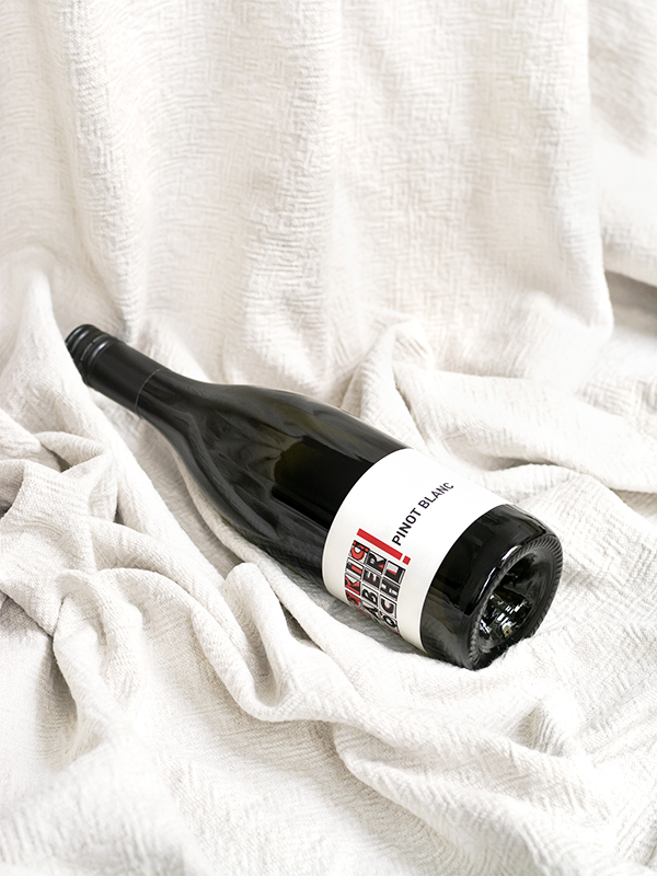 Eine Flasche Pinot Blanc vom Weingut Faber-Köchl liegend auf einer weißen Decke